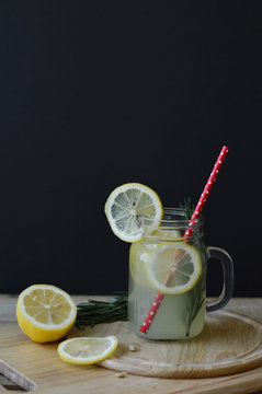 Homemade lemonade with fresh rosemary and lemon in glass jar with red straw