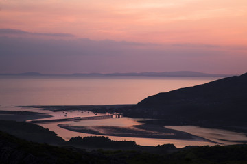 View of Barmouth and the railway bridge at sunset showing train going across bridge
