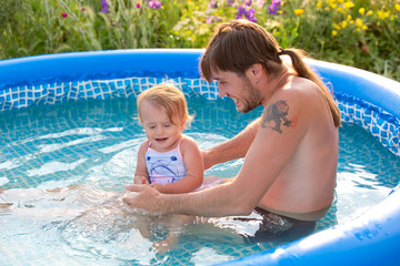 Dad and daughter in the paddling pool outdoors