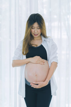 Beautiful pregnant woman touching care her belly