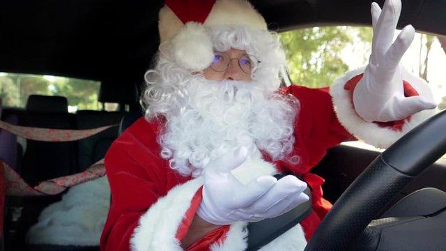 Happy Santa Claus playing with hat while driving car dancing