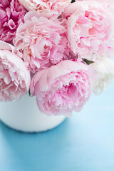 Pink fresh pink peony flowers in vase close up on blue table