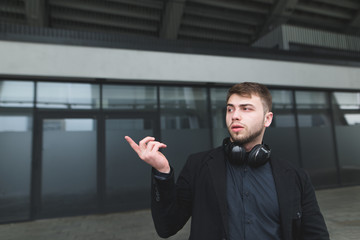 A young businessman with a beard shows a finger aside. Street portrait of a serious man with...