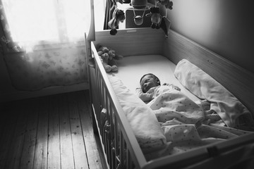One week old baby boy sleeping in his bed