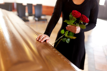 woman with red roses and coffin at funeral