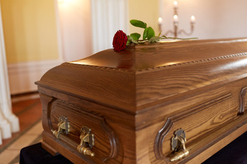 red rose flower on wooden coffin in church