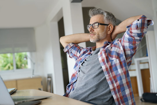 Home-office worker stretching arms in front of laptop