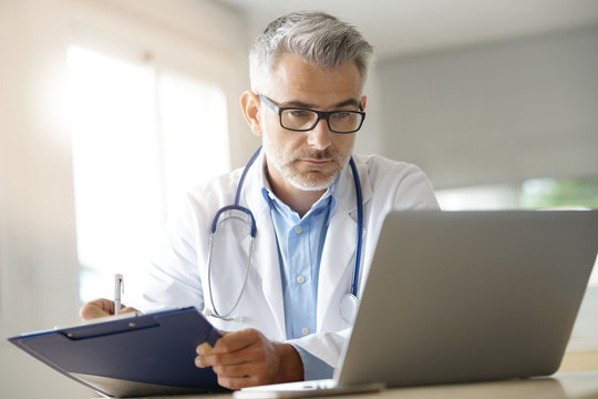 Doctor In Office Working On Patient File