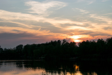 Fototapeta na wymiar Beautiful panoramic Sunset by the forest across the lake 