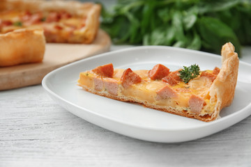 Plate with slice of delicious sausage casserole on table