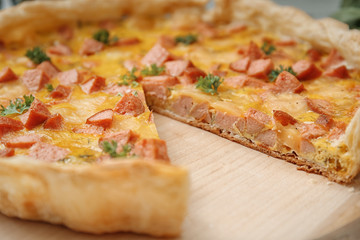 Closeup of delicious cut casserole with sausages on wooden board