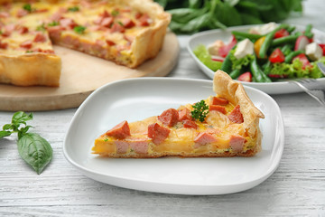 Plate with slice of delicious sausage casserole on table