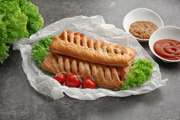 Delicious sausage rolls on table