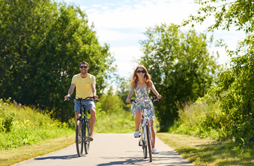 happy young couple riding bicycles in summer