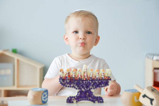 Boy with handmade nine-branched menorah at home