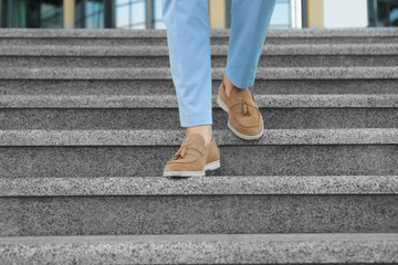 Legs of successful businessman walking down stairs outdoors