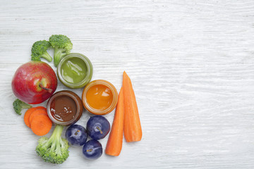 Jars with different baby food and ingredients on table