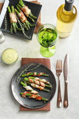 Fototapeta na wymiar Plate with bacon wrapped asparagus on table
