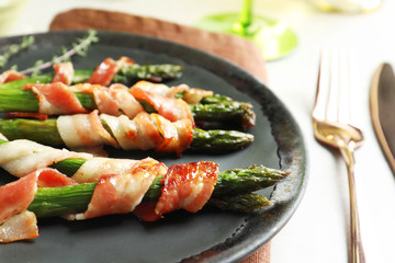 Plate with bacon wrapped asparagus on table, closeup