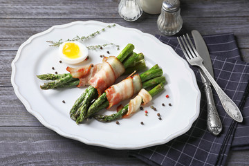 Plate with bacon wrapped asparagus on table