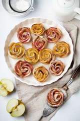 Delicious pies with an apple rose in ceramic form on a light concrete or stone background. Selective focus. Top view.