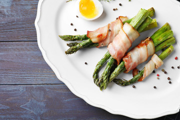 Plate with bacon wrapped asparagus on table