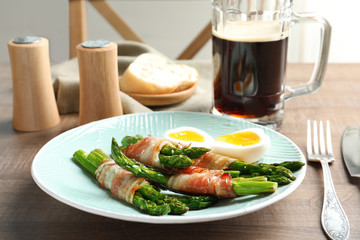 Plate with bacon wrapped asparagus on table