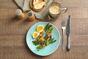 Plate with bacon wrapped asparagus on table