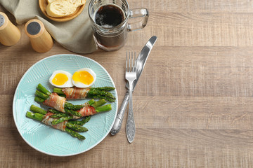 Plate with bacon wrapped asparagus on table