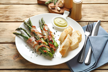 Plate with bacon wrapped asparagus on table