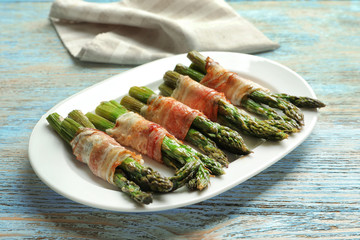 Plate with bacon wrapped asparagus on table