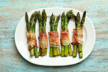Plate with bacon wrapped asparagus on table