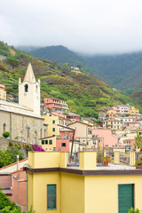 Fototapeta na wymiar View to buildings and mountains in a foggy day. Vernazza, Cinque Terre, Italy