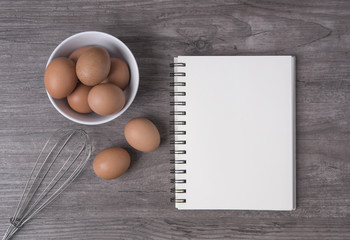 egg with open recipe book on wooden table, Top view