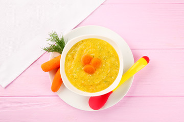 Plate of creamy baby vegetable soup on wooden table