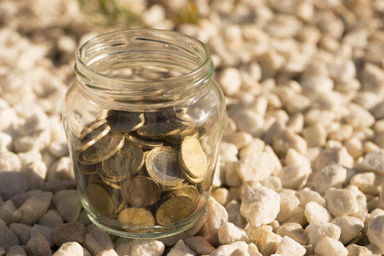A transparent jar with many coins saved
