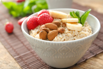 Tasty oatmeal with fruits in bowl on table