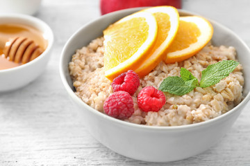 Tasty oatmeal with fruits in bowl on table