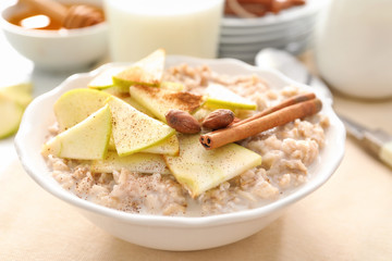 Nutritious oatmeal with apple and almonds in plate, close up