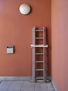 Ladder, ashtray and lamp on a red wall