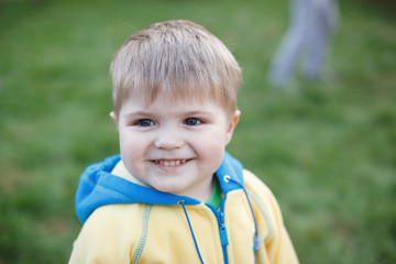 Little baby boy with blue eyes and blond hairs close up outdoors in park