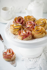 Delicious pies with an apple rose in ceramic form on a light concrete or stone background. Selective focus. Top view.