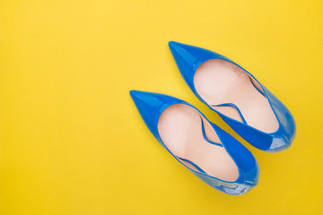 Varnished blue shoes on a yellow background