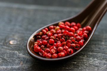 Close up pink peppercorn in spoon dark background