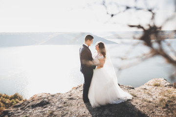 Elegant stylish happy wedding couple, bride, gorgeous groom on the background of sea and sky