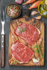 Fresh organic raw beef. Ingredients for making dinner - steaks, onion, garlic, rosemary, salt, pepper, olive oil. Selective focus