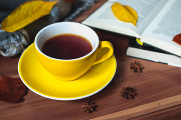 Yellow cup of tea with books and autumn leaves