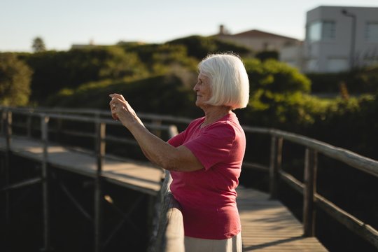 Senior woman clicking pictures on the bridge