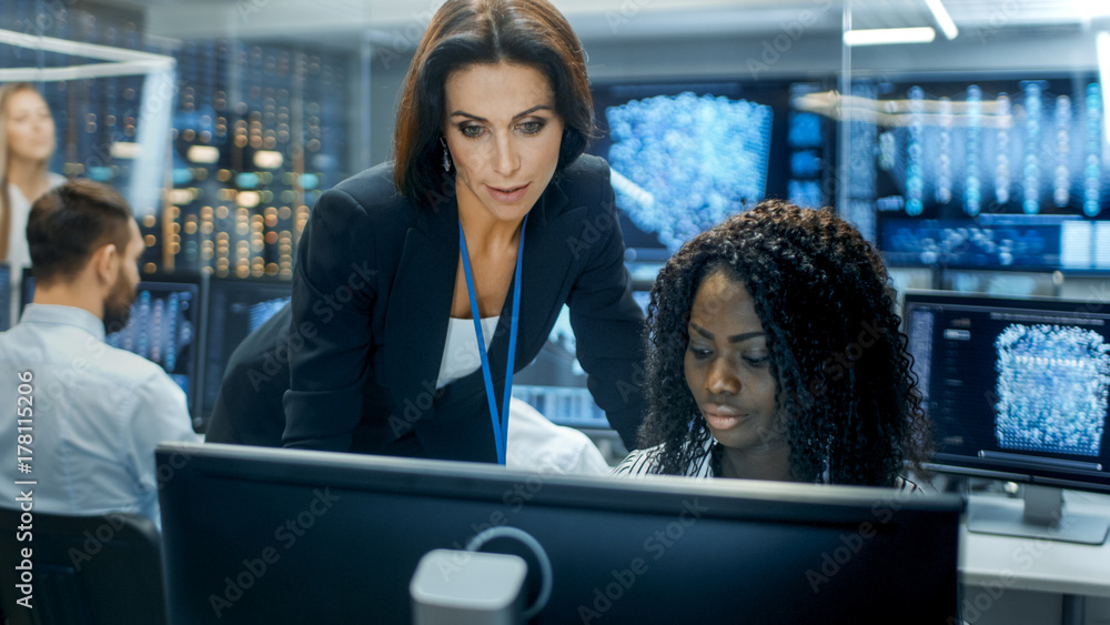 Poster Female Team Leader Consults Young Computer Engineer. They Work in a Crowded Office on a Neural Network/ Artificial Intelligence Project.