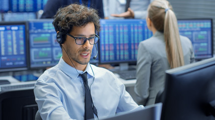 Stock Trader Making Sales with a Headset. In the Background Stock Exchange Office and Group of...